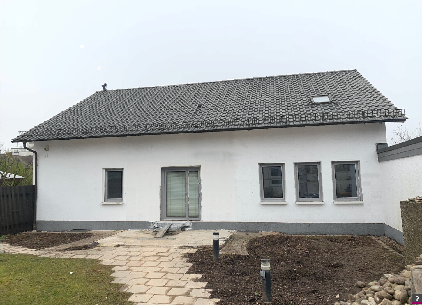 Exterior view of a white detached house with a pitched roof and roofing work