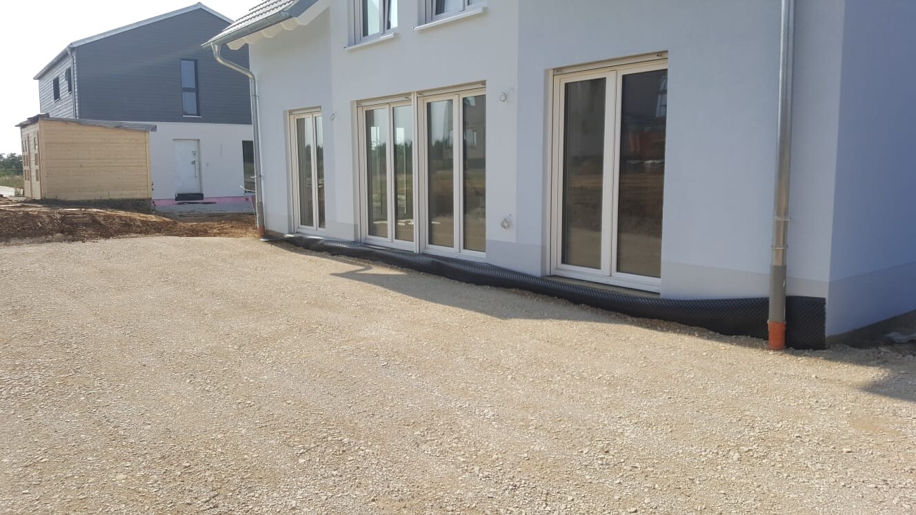 White house facade with large glass sliding doors, gravel floor and construction area nearby