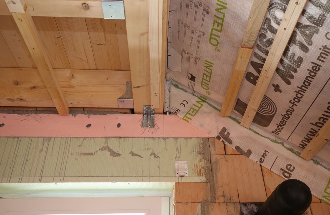Attic with wooden frame, pink insulation boards, metal fittings, and pipes.