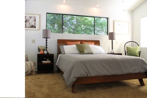 Bright bedroom with wooden bed frame, nightstands, lamps, and large window front