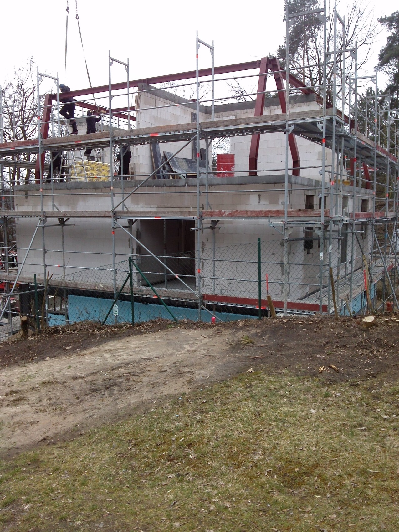 Construction site with scaffolding around a multi-story shell; workers are working on top.