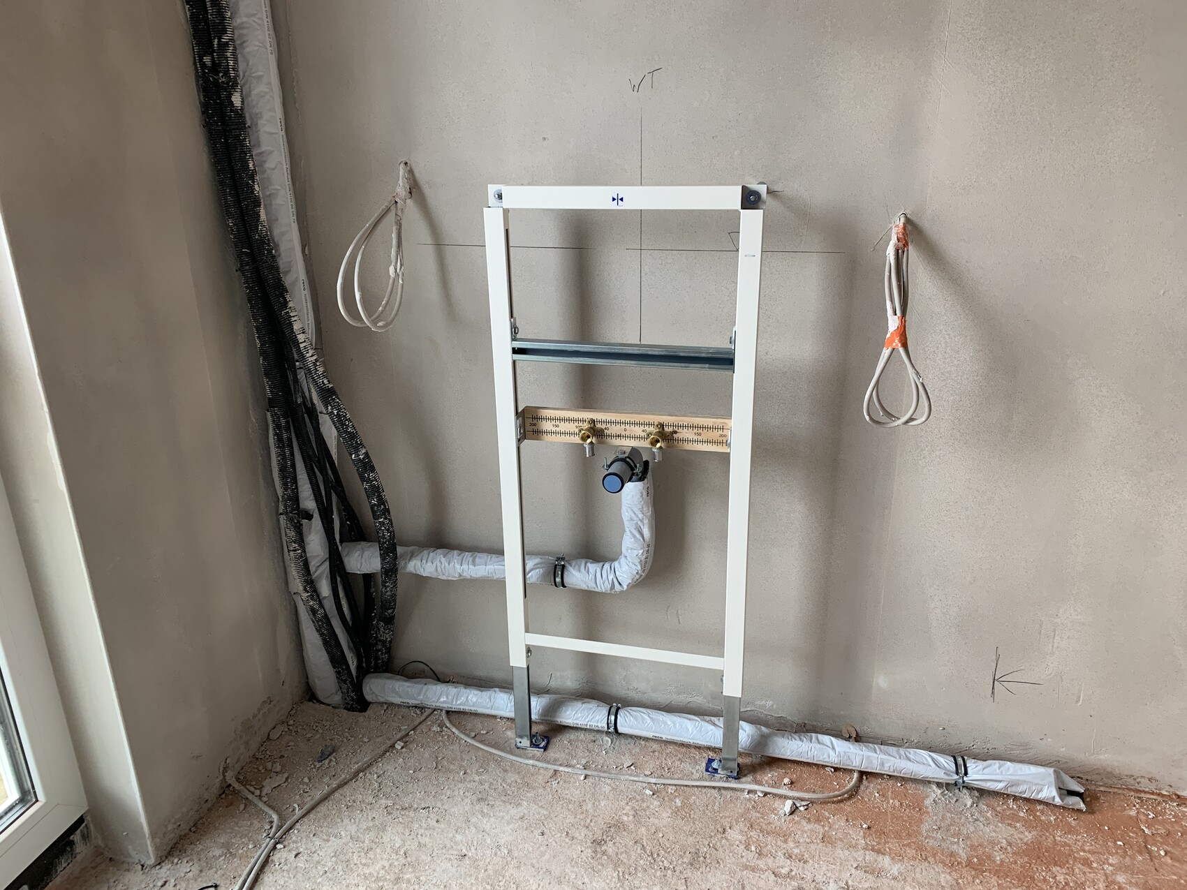 White installation frame for wall-hung toilet with drain pipe and water connections.