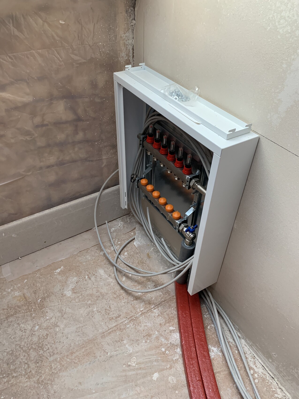 Open electrical distribution box with many cables, red clamps, and orange buttons