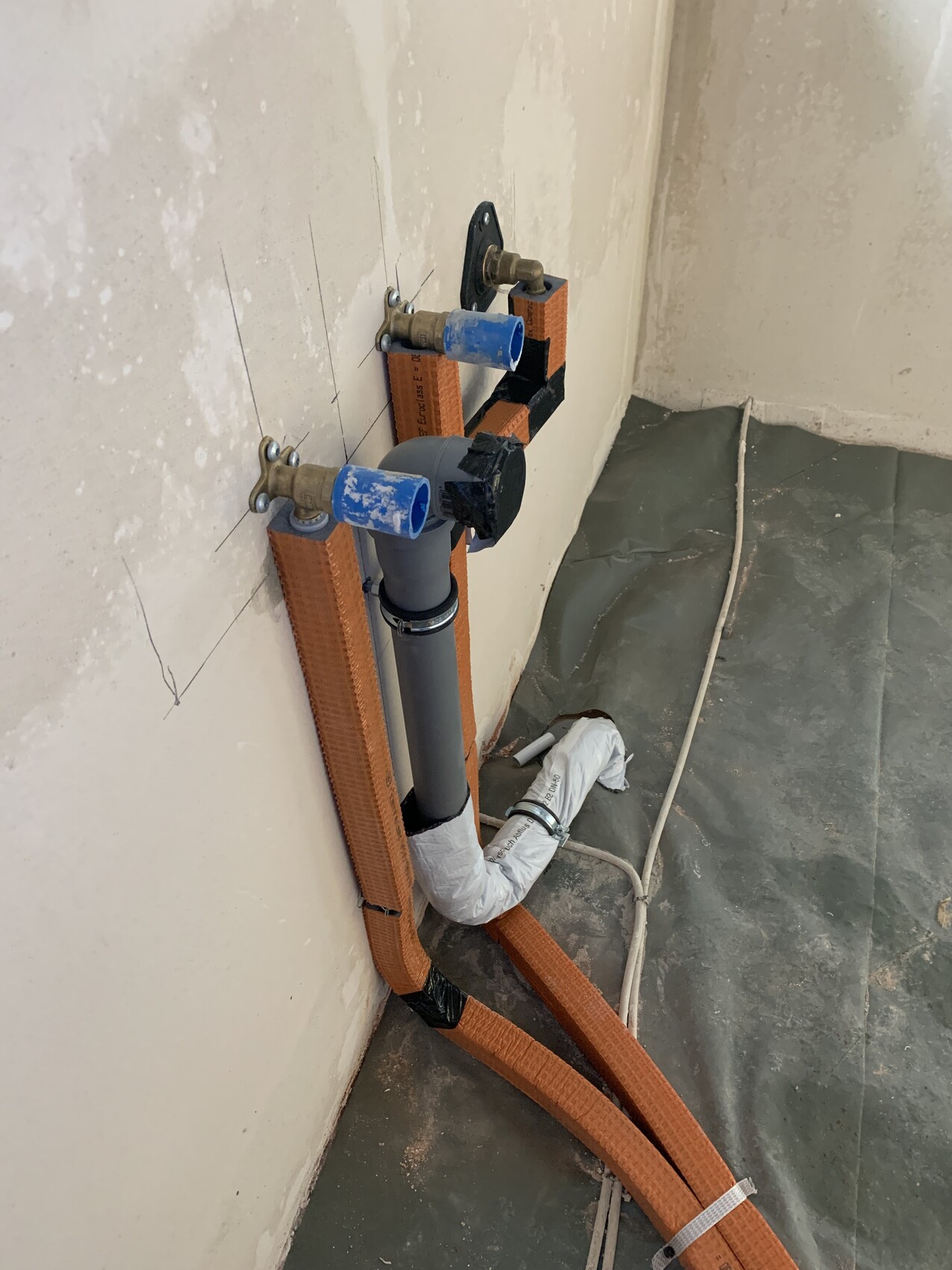 Drain and trap pipe on the wall, blue valve, orange straps.