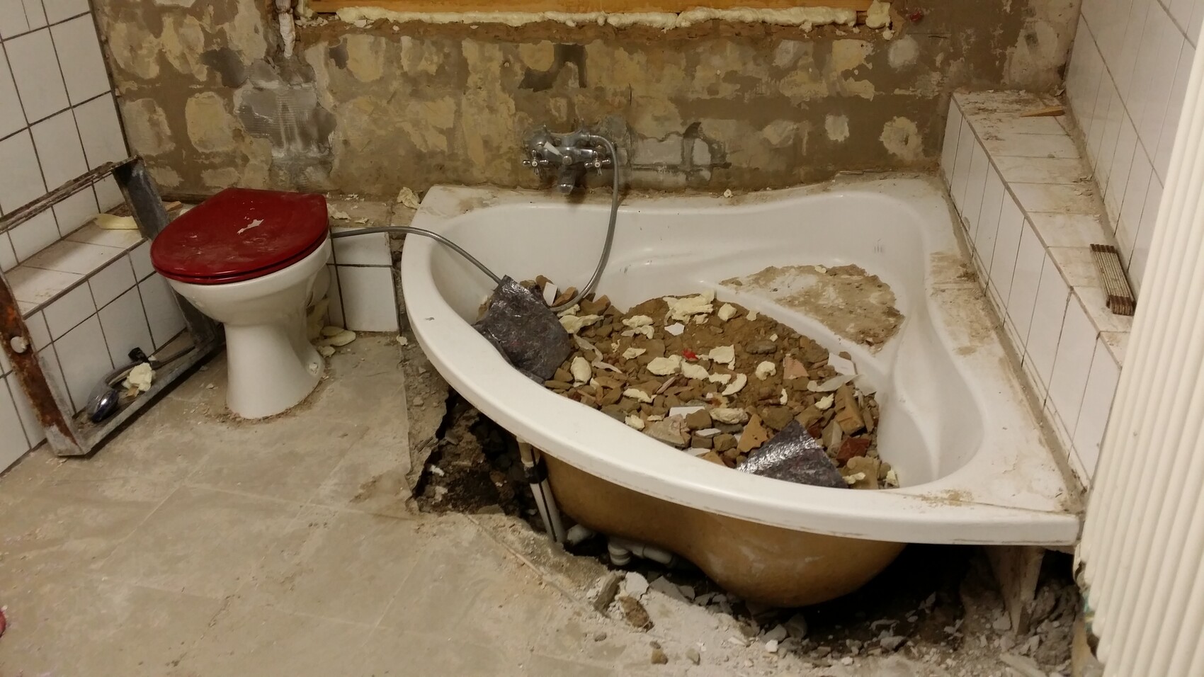 Bathroom under renovation with exposed bathtub and mortar residues
