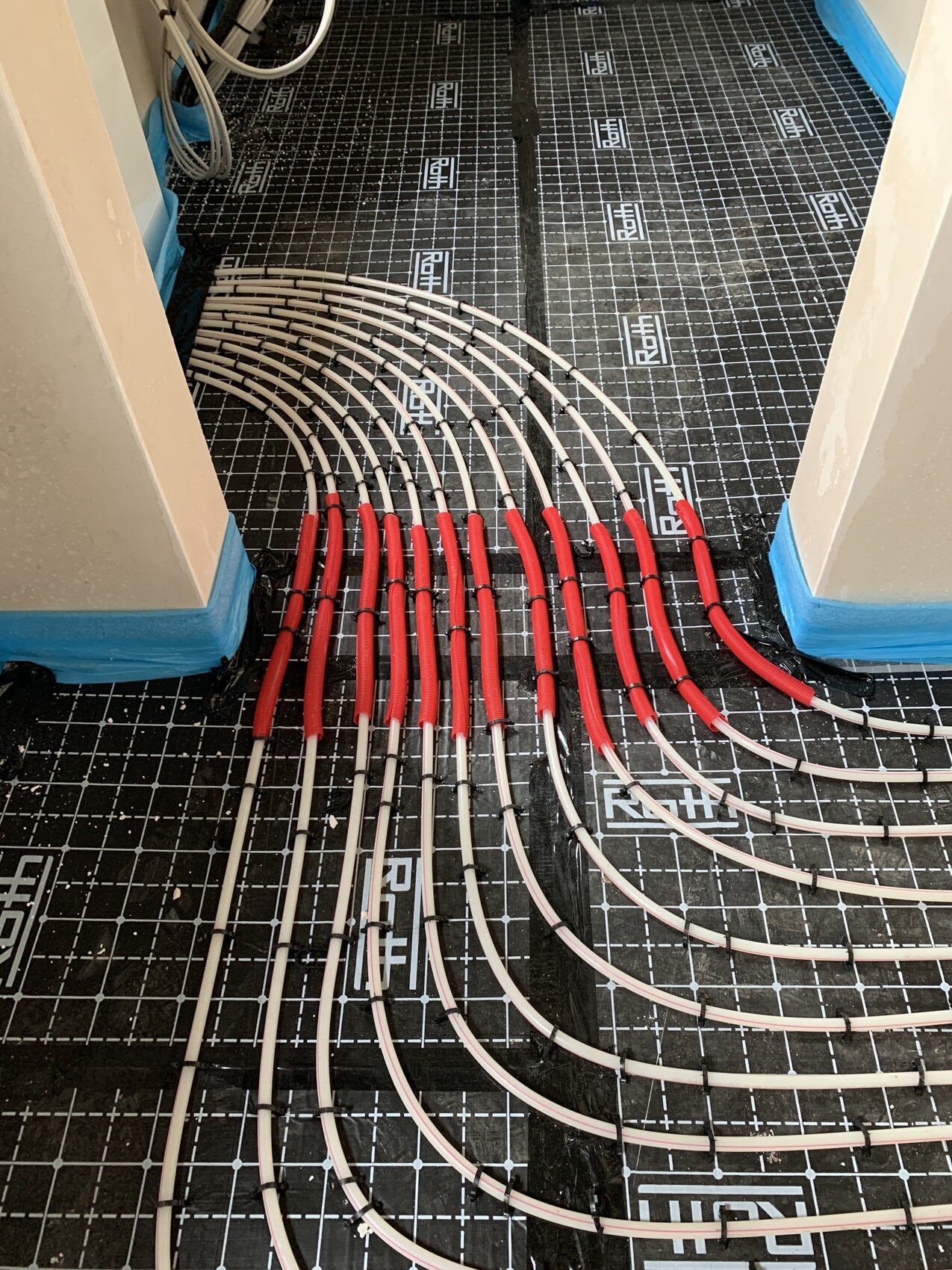 Underfloor heating: red PEX pipes laid in U-shaped loops on black insulation.