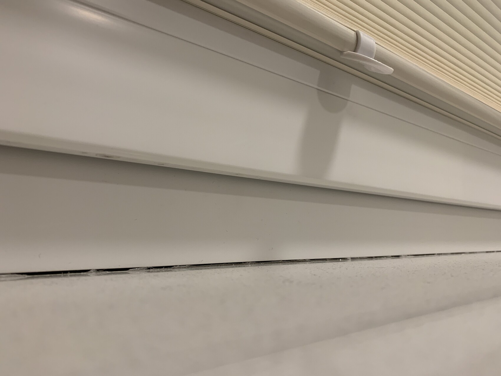 Close-up of a white window shutter, guide rail, and cover panel