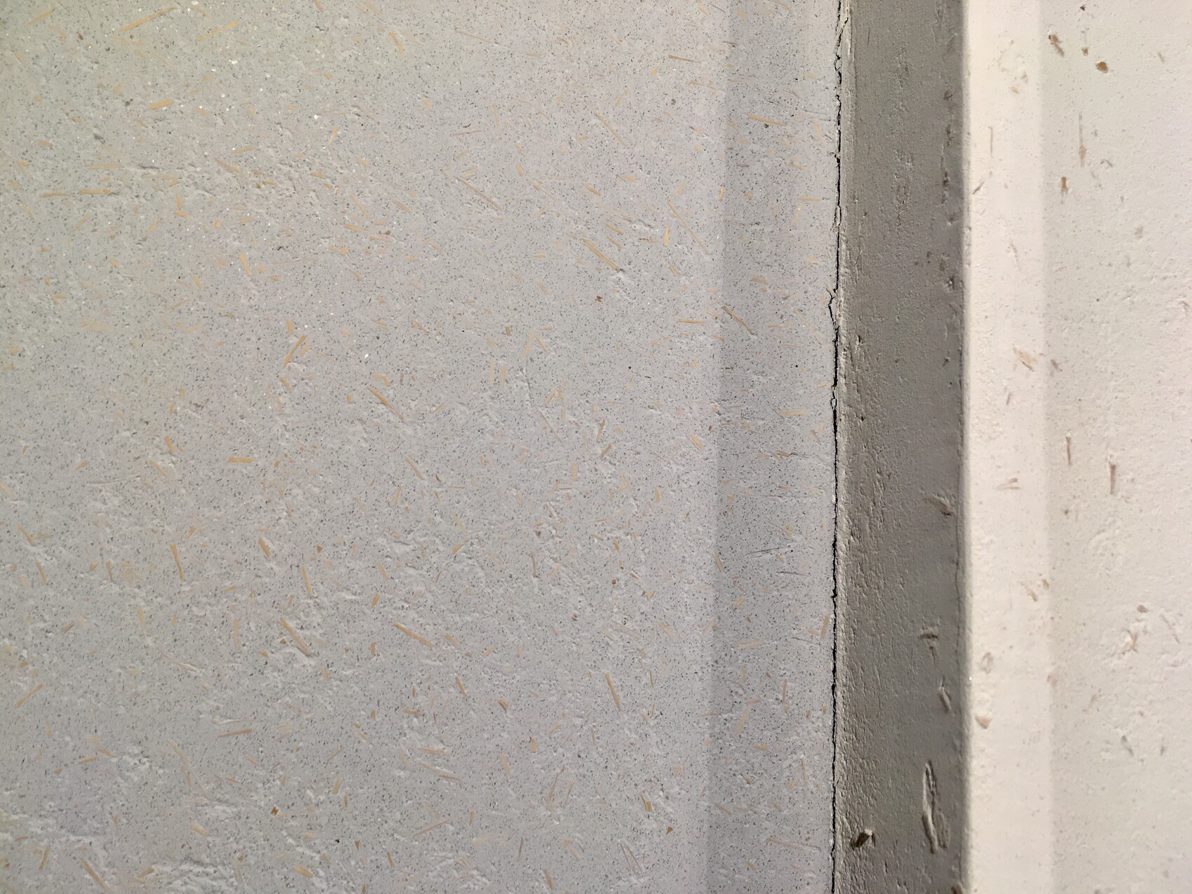Close-up of a grey wall area with scattered orange wood chips; gap at the right edge.