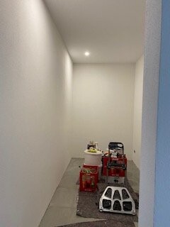 Heller, schmaler Flur mit weißen Wänden und Werkzeugkisten am Boden.