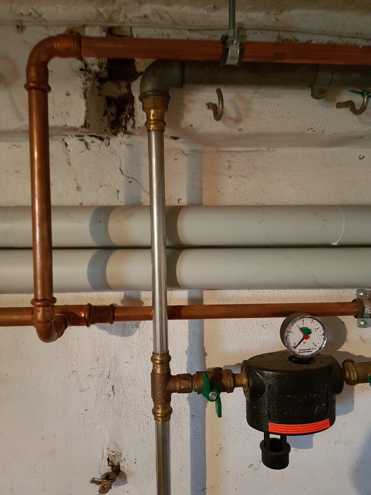 Heating system: copper pipes, shut-off valves, pressure gauge, and circulation pump on the wall.