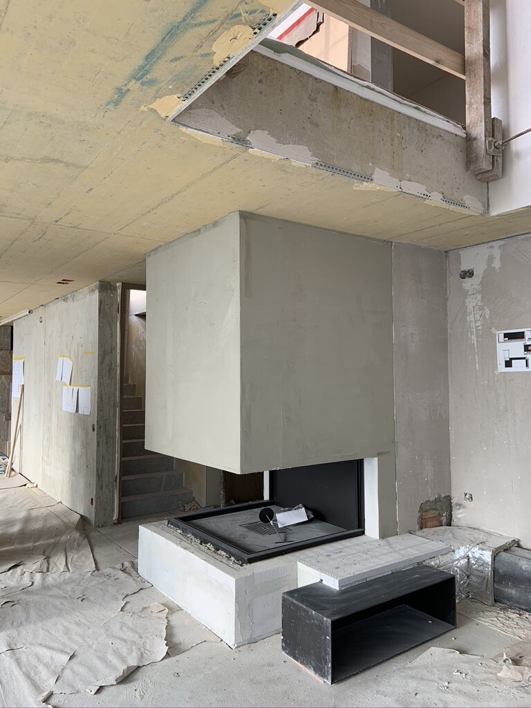Unfinished interior with concrete fireplace structure and firebox behind glass.