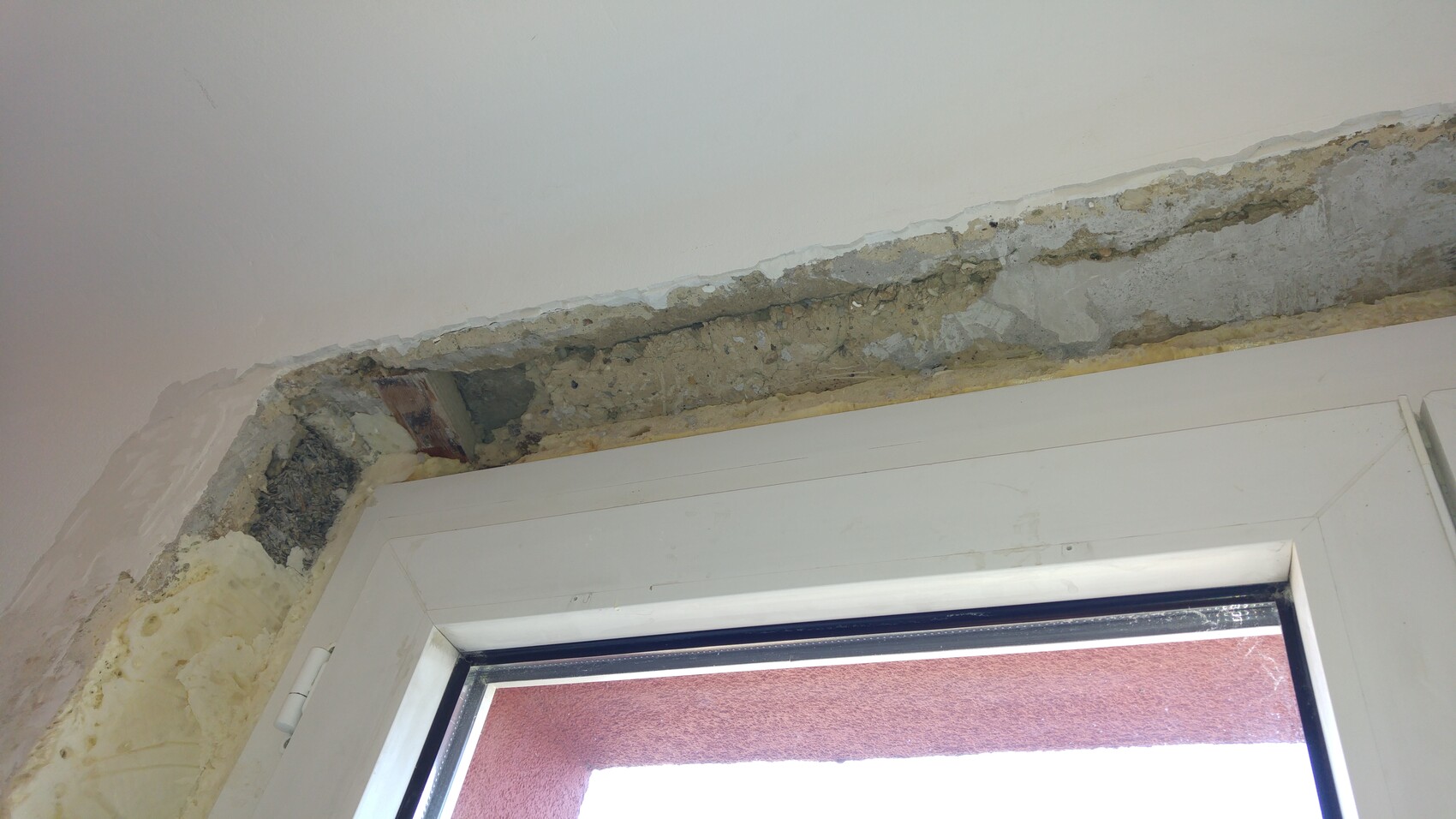 Damaged interior wall around window with flaking plaster and moisture