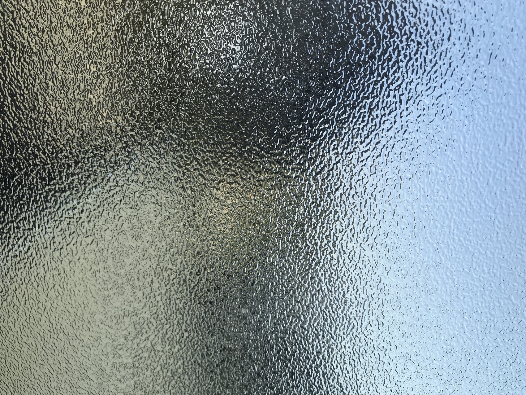 Frosted, textured glass window; irregular patterns from dark on the left to light on the right.