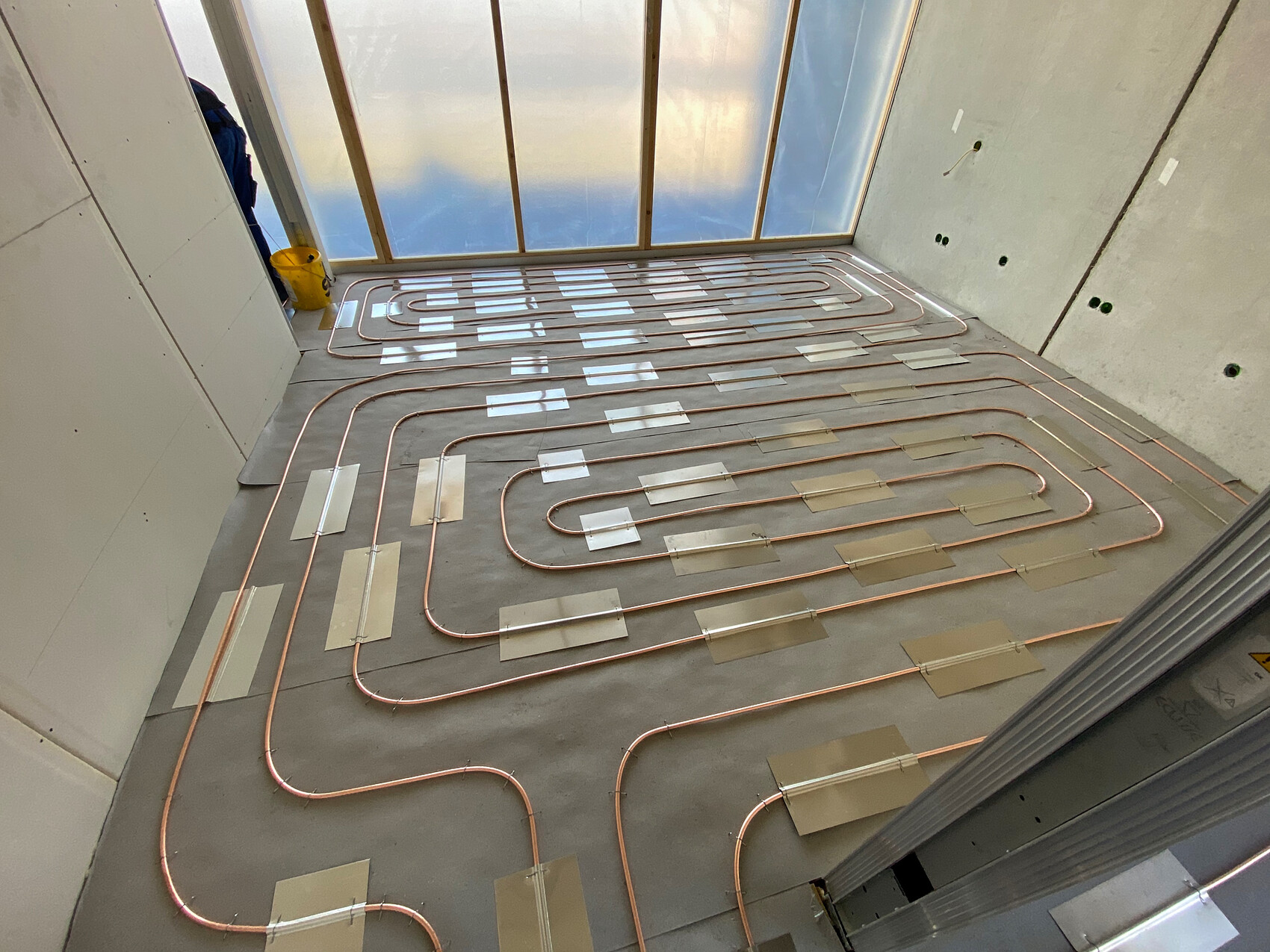 Unterflur-Heizrohr-Verlegung: Kupferrohre in Schleifen auf Betonboden, Neubau, Fensterfront