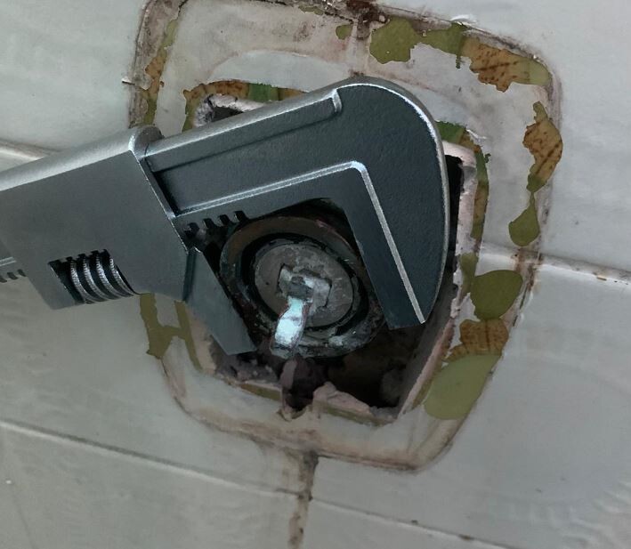 Nahaufnahme einer verstellbaren Zange an Sanitäranschluss hinter Fliesen im Badezimmer