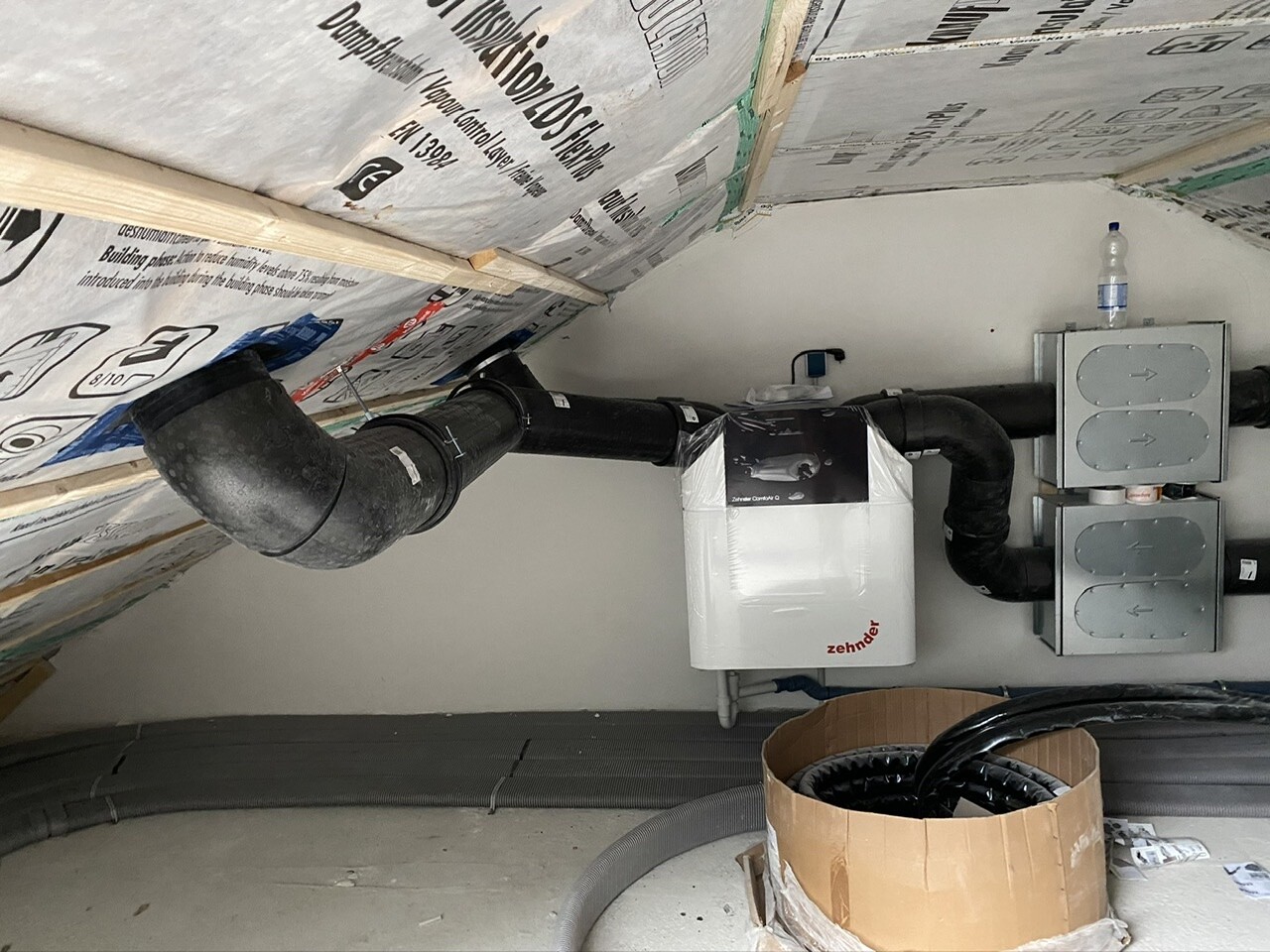 Attic ventilation system: black ductwork, white Zehnder heat exchanger, distribution boxes.