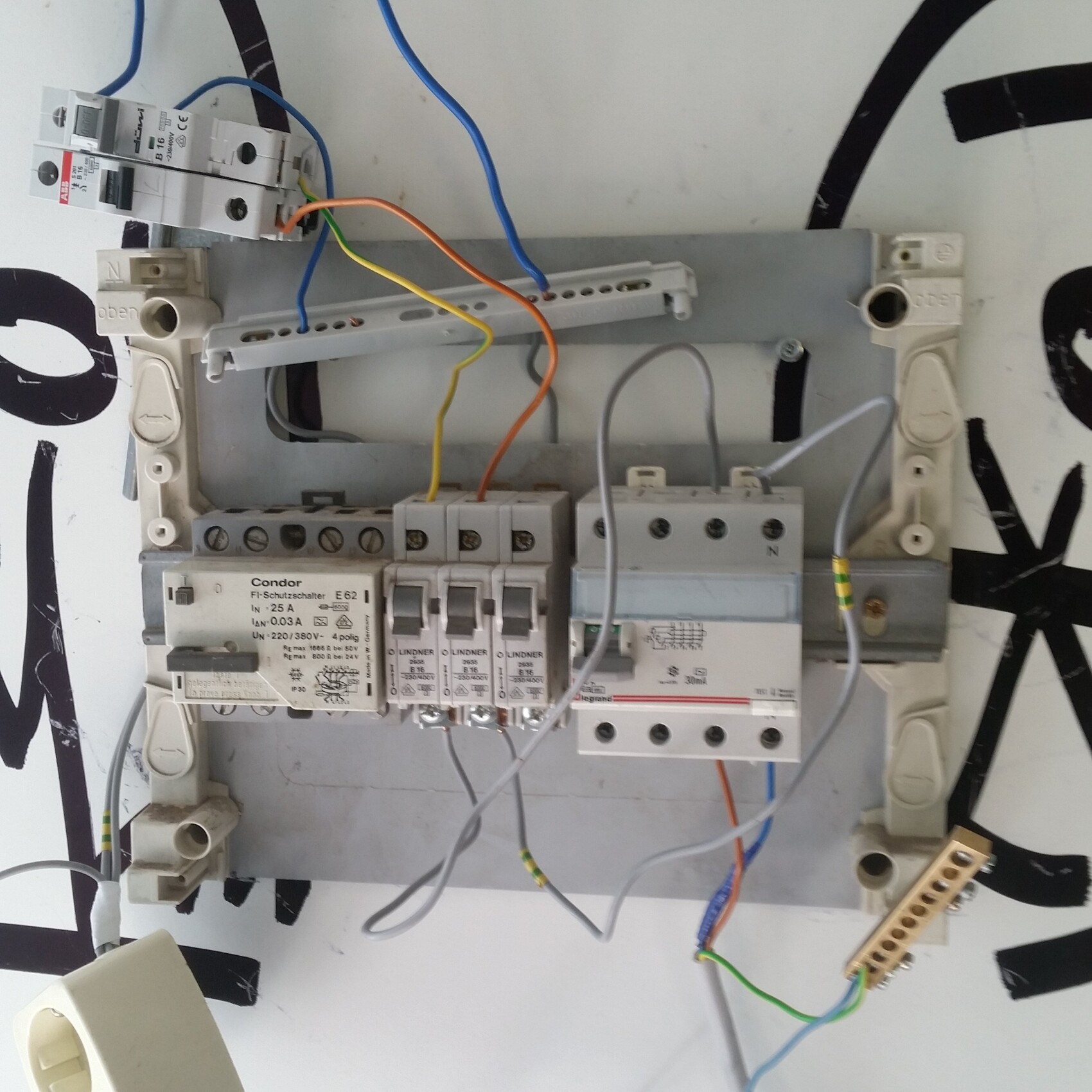 Elektrischer Verteilerkasten mit Sicherungen, Kabeln und Steckleisten.
