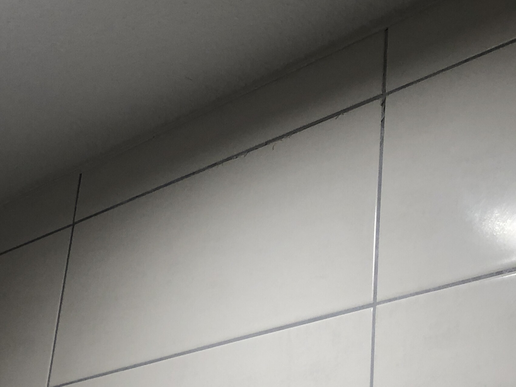 Light gray wall tiles with dark grout, diagonal perspective.