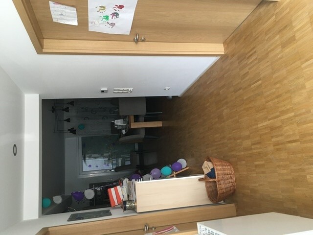 Living room with wooden floor, basket, colorful balloons, stack of books and table in the background.