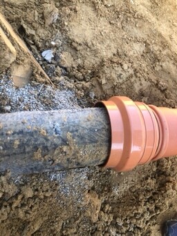 Underground orange sewer pipe in the ground, earthworks visible