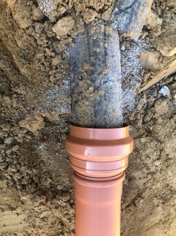 Close-up of an orange PVC pipe in the ground during construction work
