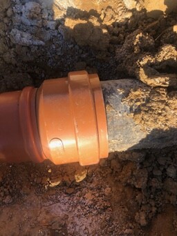 Orange PVC pipe connection in the ground, soil around