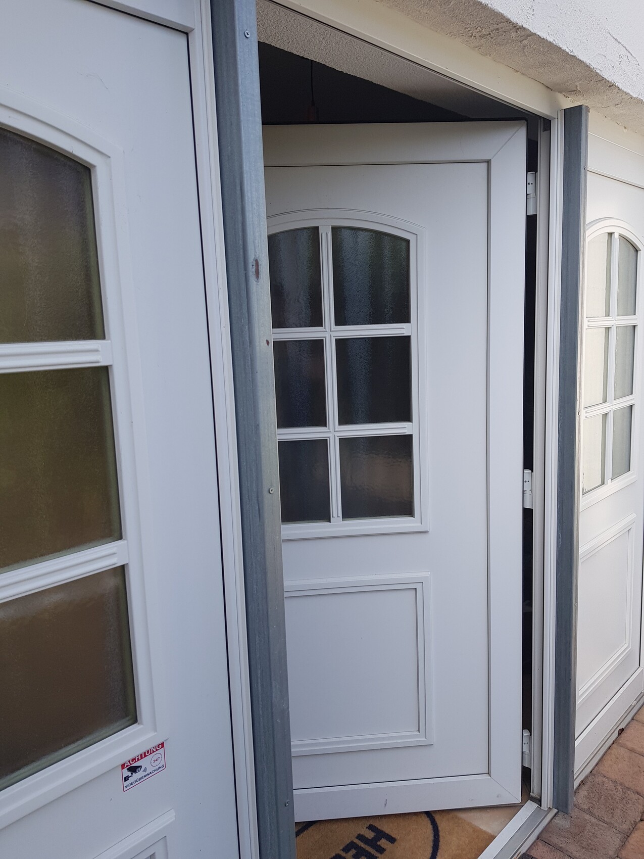 White front door with six windows in a grid design, open in the entrance area.