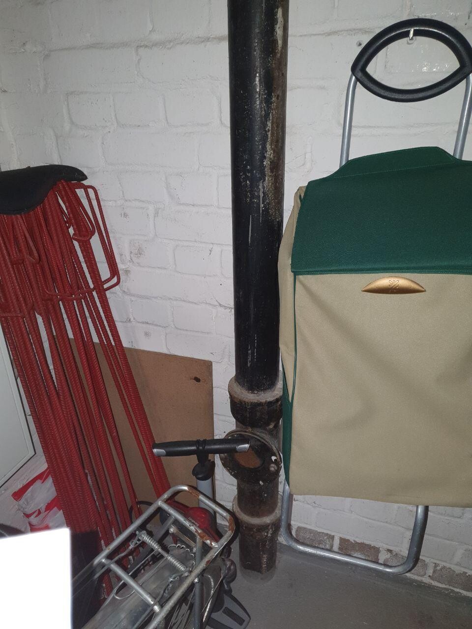 Basement room with large black pipe and storage items