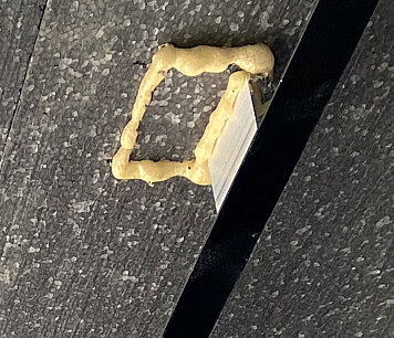 Wall joint with yellow foam insulation on dark stone surface
