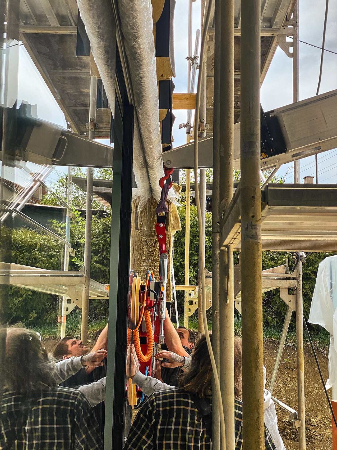 Several workers mounting a lifting and safety system on a glass facade on scaffolding.