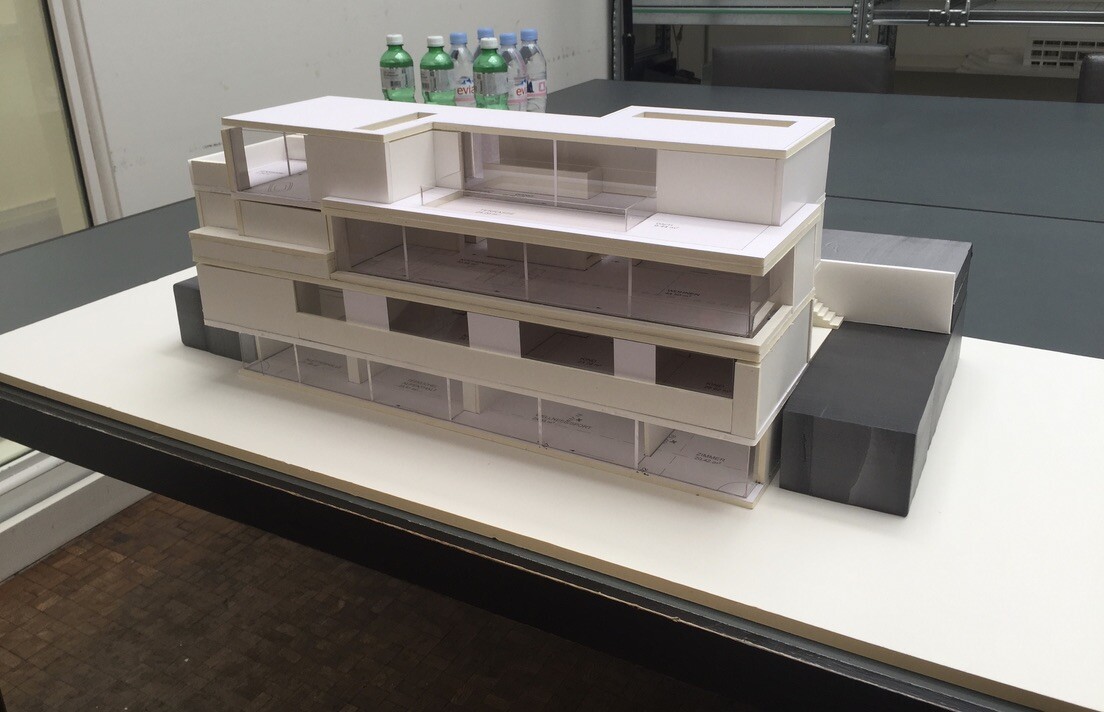 Architectural model of a modern, multi-story white building with glass facades.