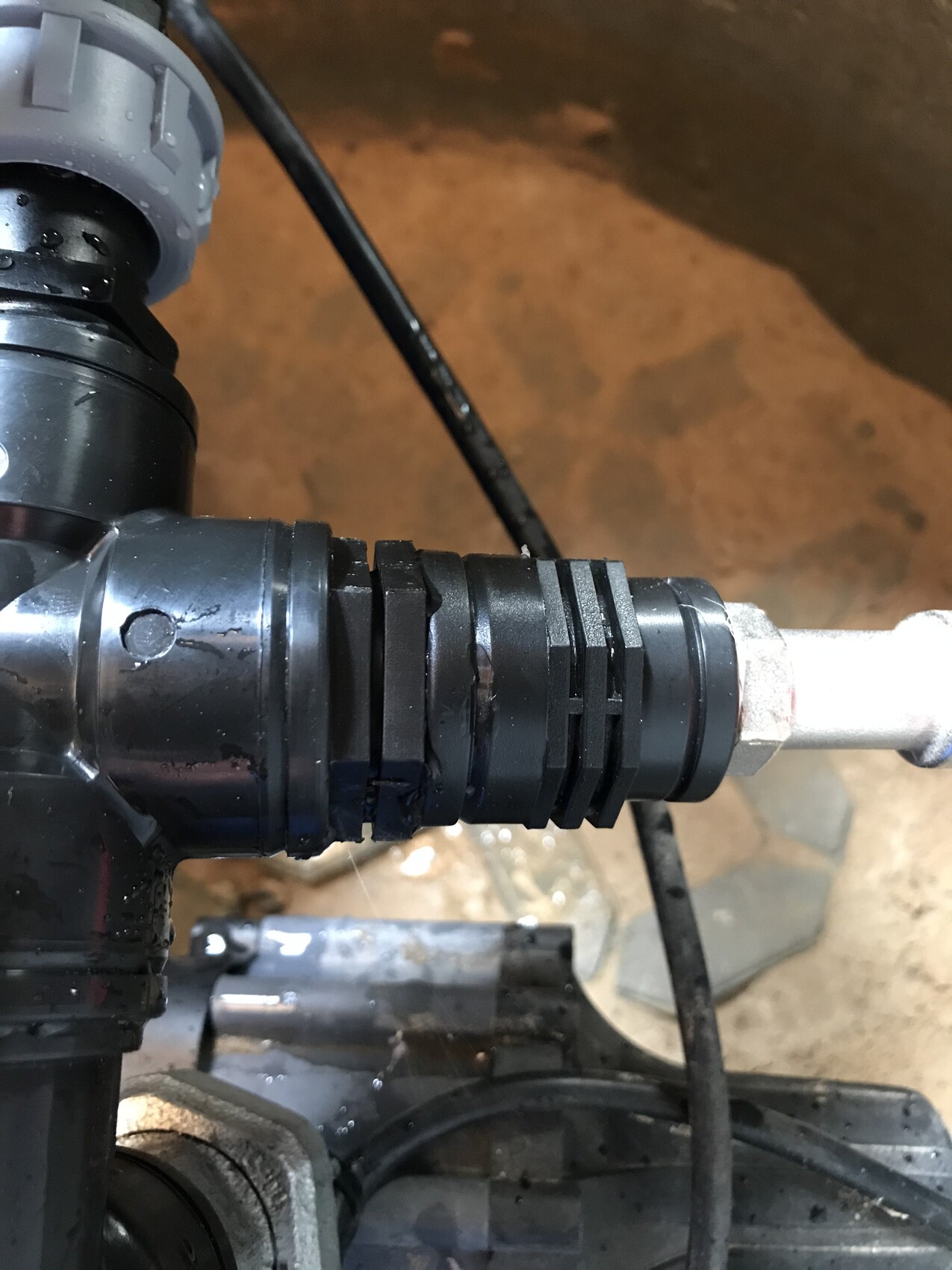 Black multipart plastic coupling on a metal pipe.