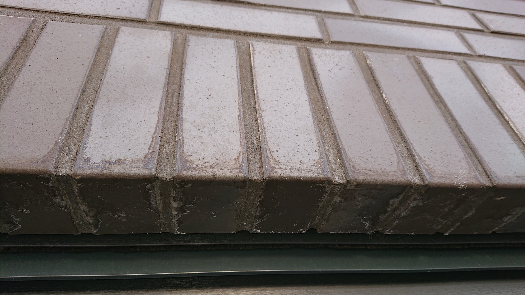 Close-up of gray concrete roof tiles on a roof edge.
