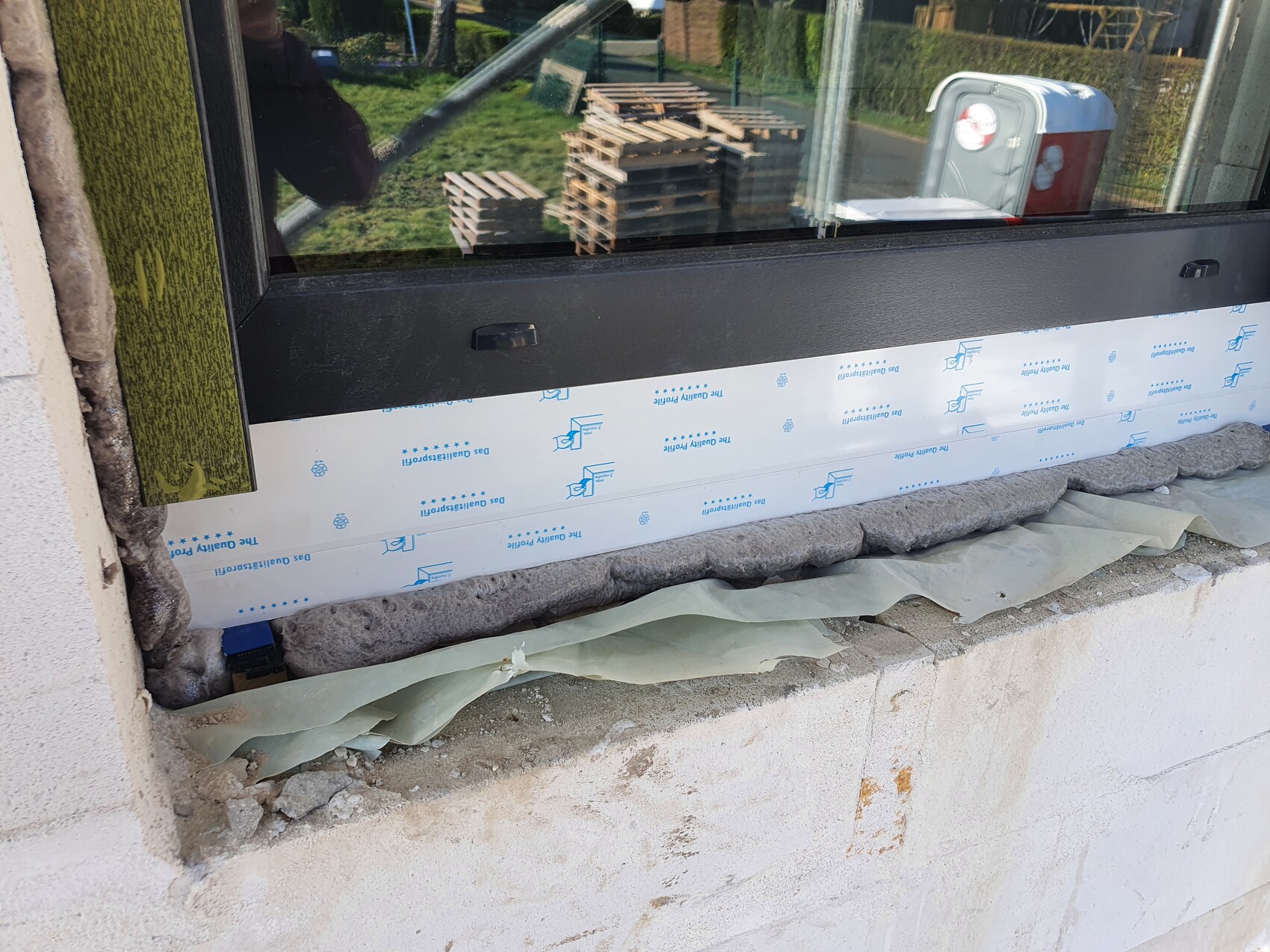Window frame being installed at a construction site, protective film and insulation visible