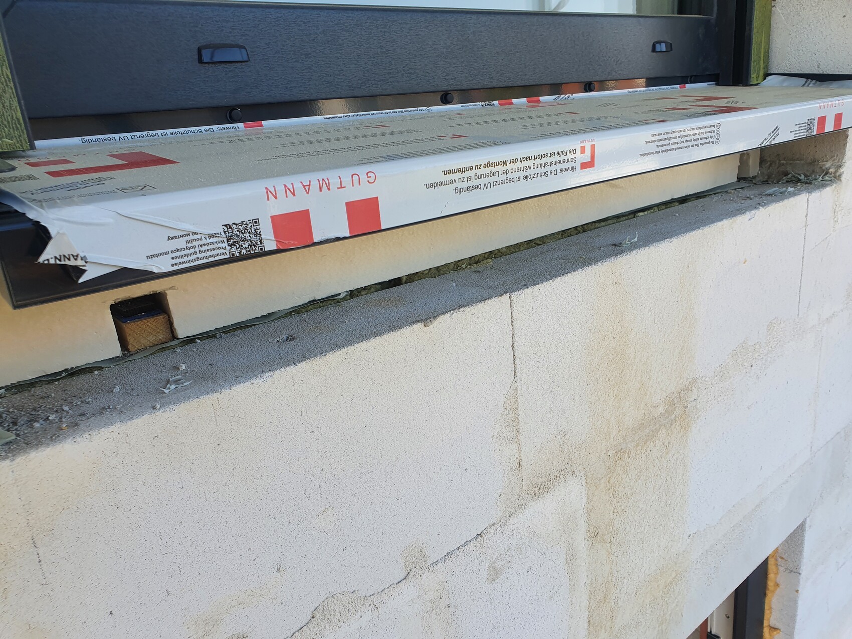 Window frame installed over a concrete wall; packaged insulation lying on the opening.