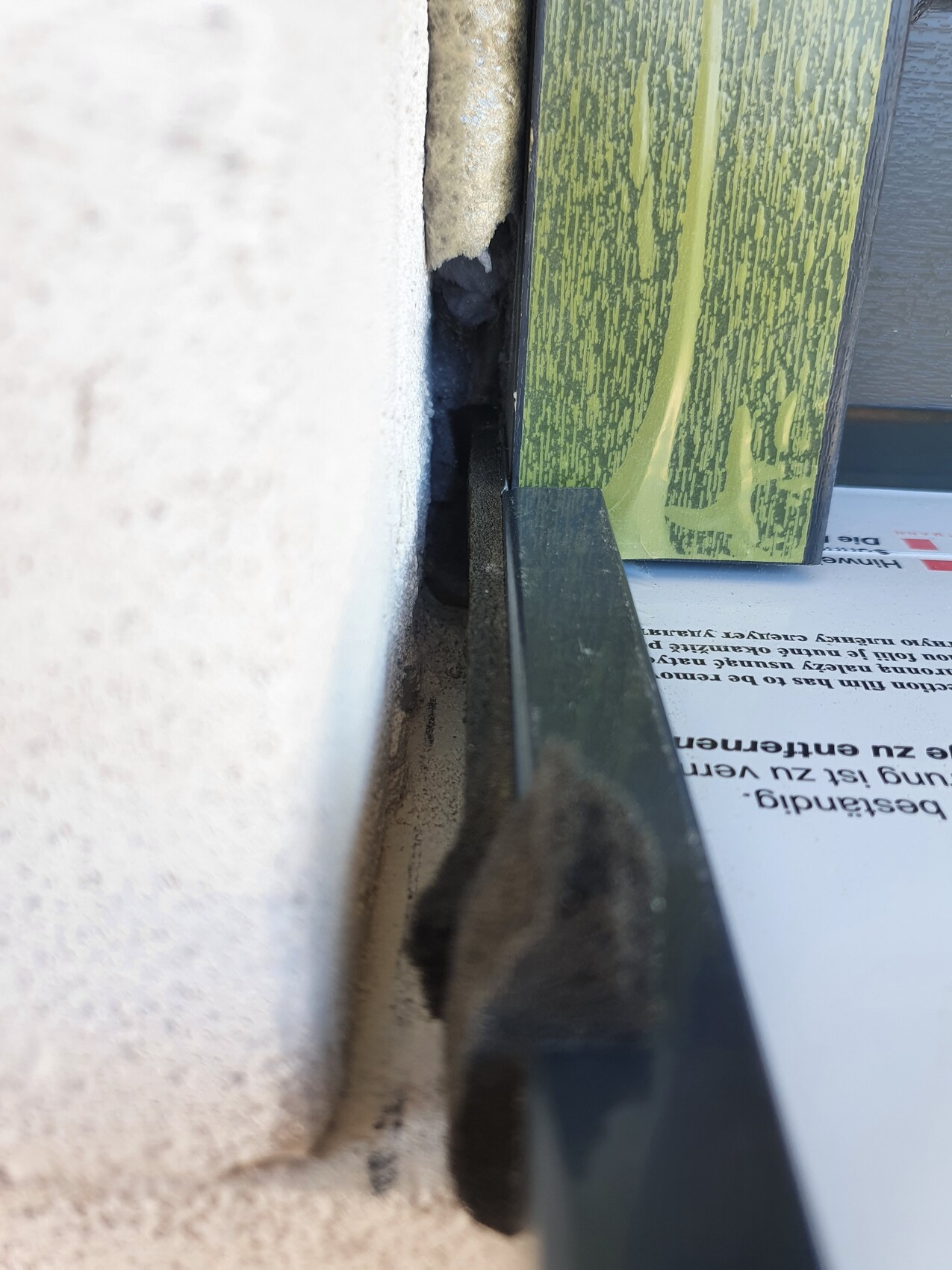 Close-up of a joint between a white wall and a green wooden frame, visible dust.