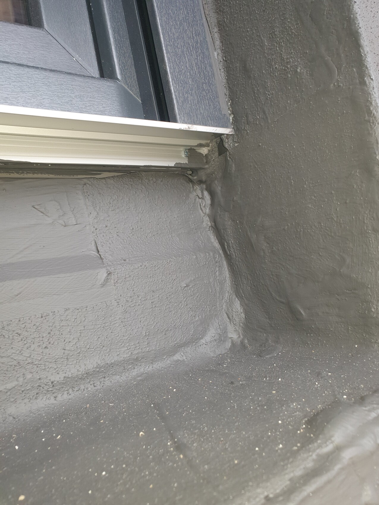 Close-up: roof window with gray sealant at the window connection on the roof.
