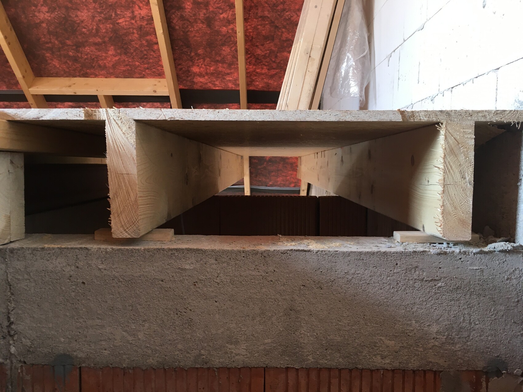 View through a wooden formwork showing the rectangular cavity of a basement ceiling between beams.
