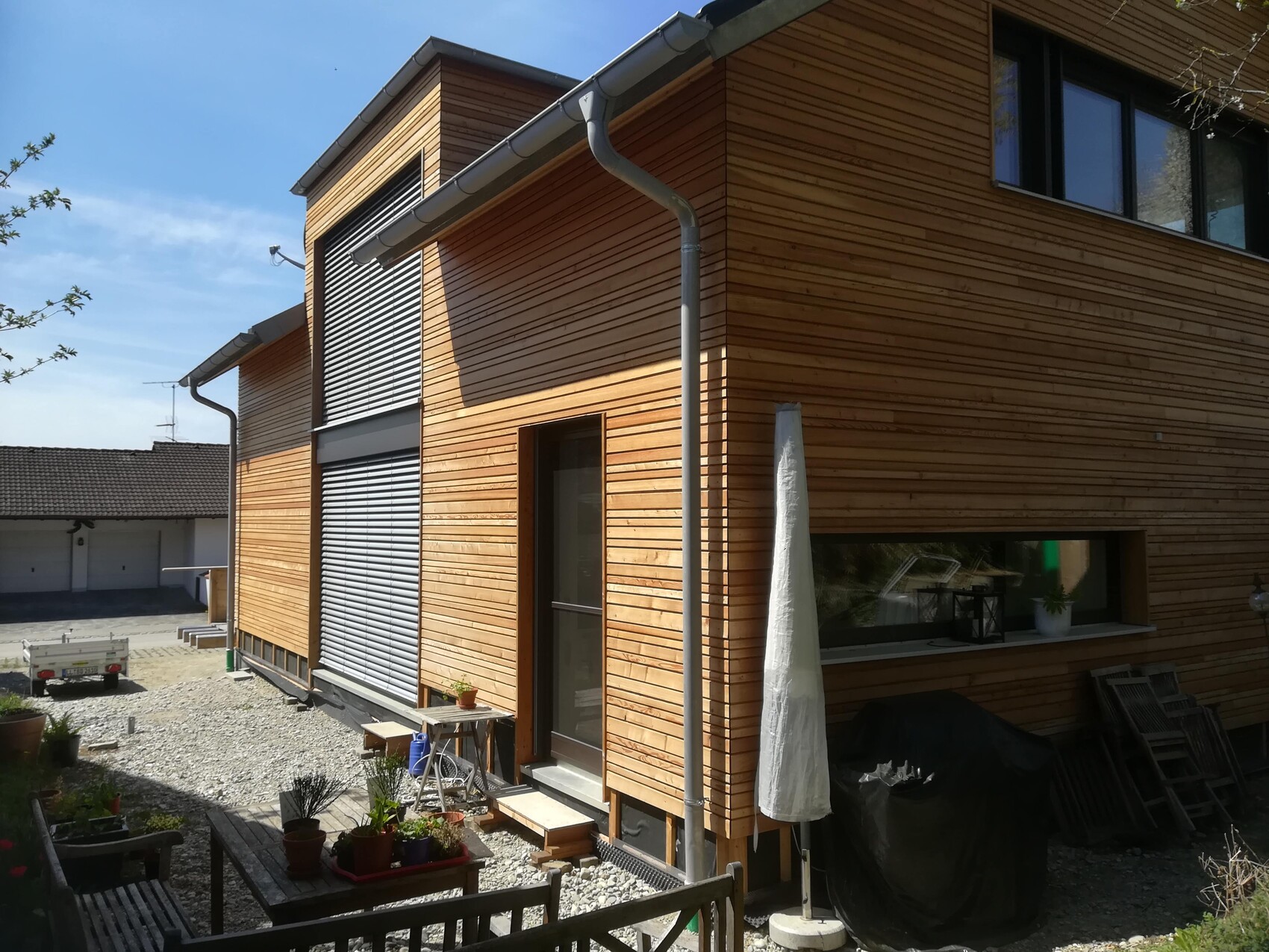 Modern wooden house with large windows, shutters, garden and terrace.