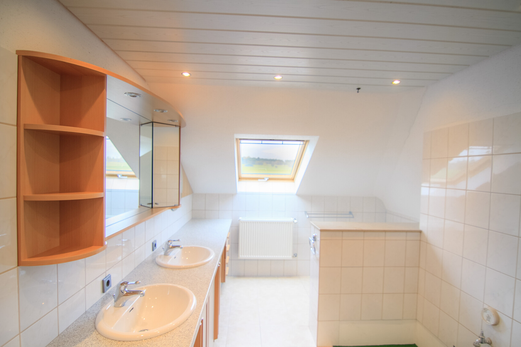 Bright bathroom with two sinks, mirrors, wooden shelf and skylight in the attic room.