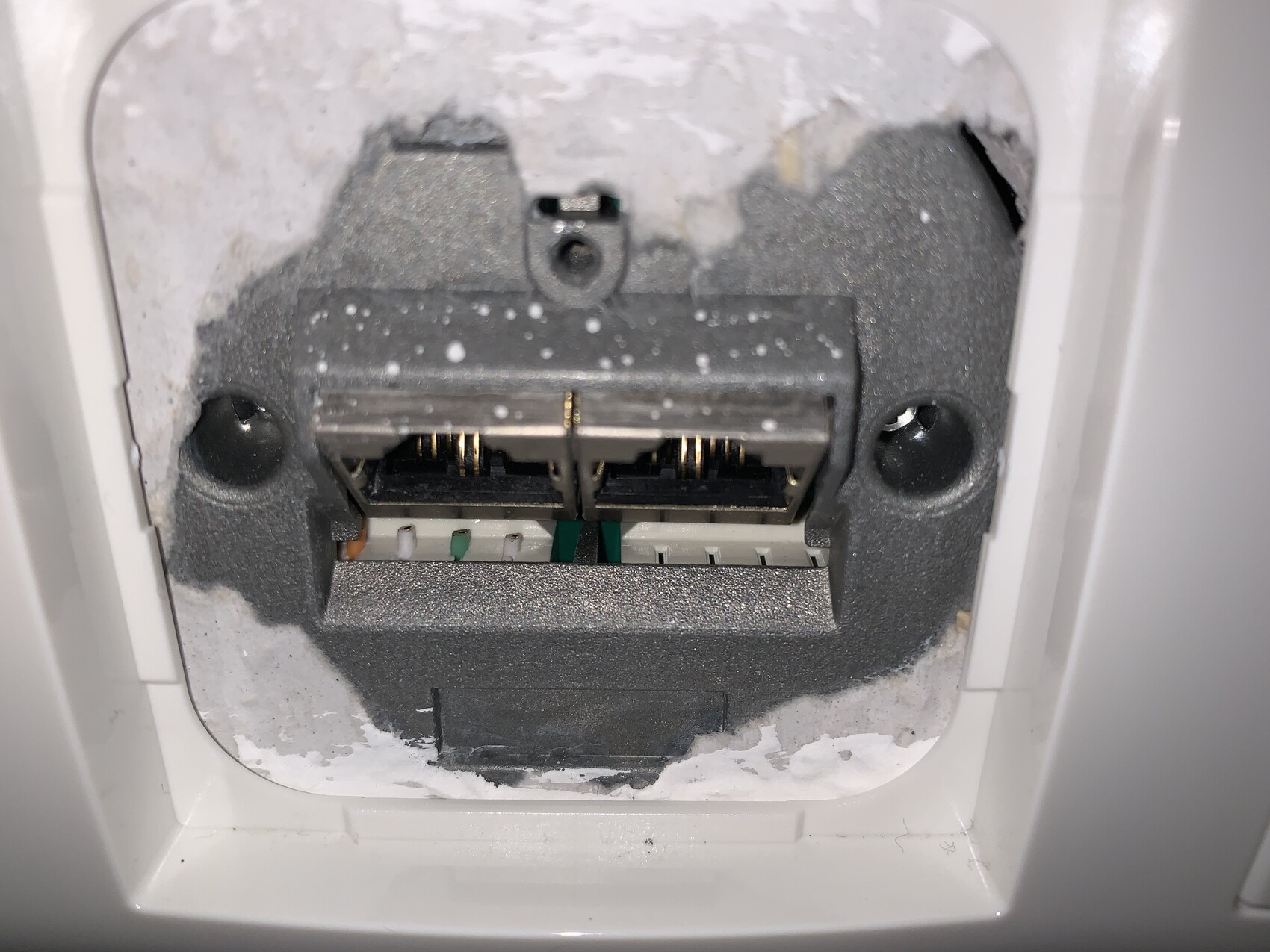 Close-up of an electrical outlet behind the wall showing dust and contacts