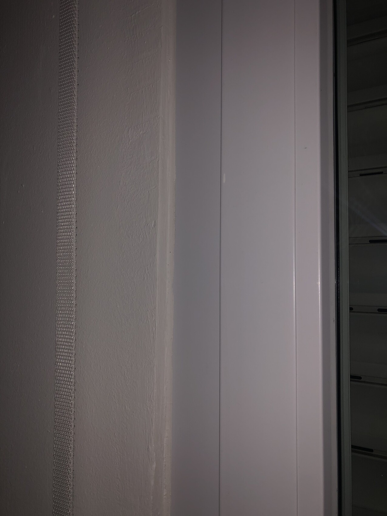 Close-up of a white window frame on a wall, with a glass window visible on the right