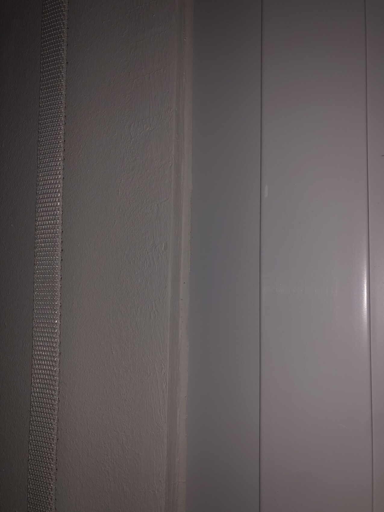 Close-up of a gray interior wall with a narrow vertical strip and smooth panels.