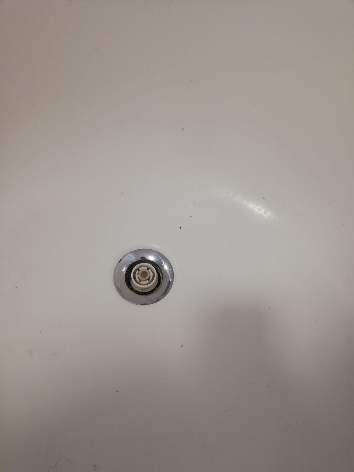 Round bathtub drain with metal rim and white inner part