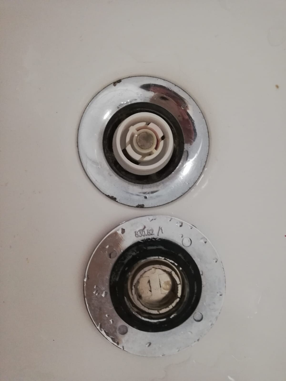 Close-up of two round wall boxes with plastic internal components on a white surface.