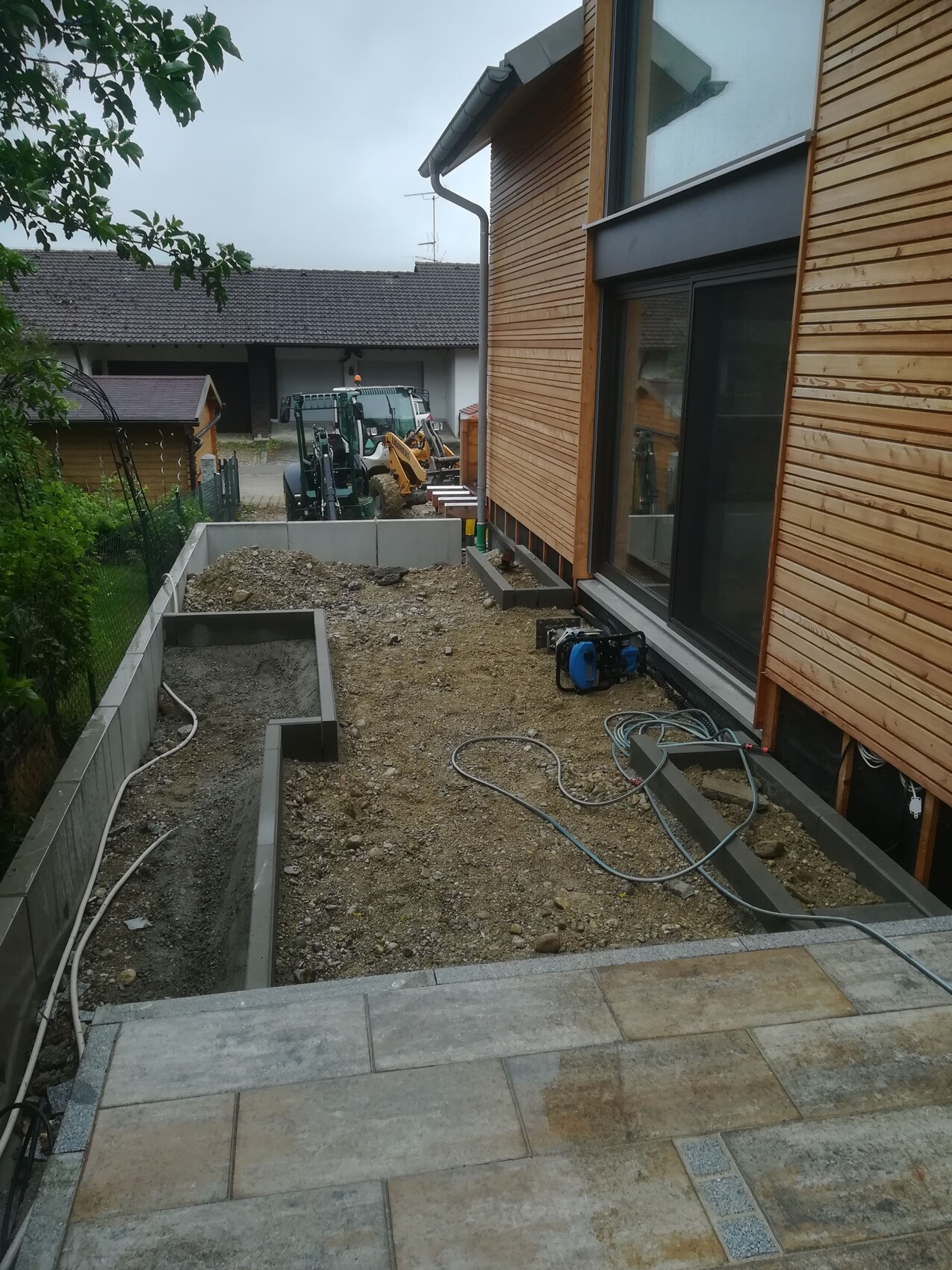 Excavation work at the wooden house: construction equipment, hoses, and generator in the garden.