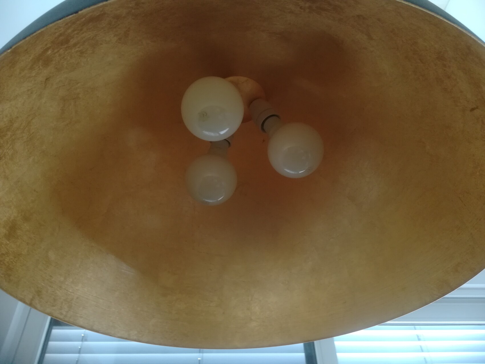 Three-light ceiling fixture with three bulbs on a golden-brown round shade, viewed from below