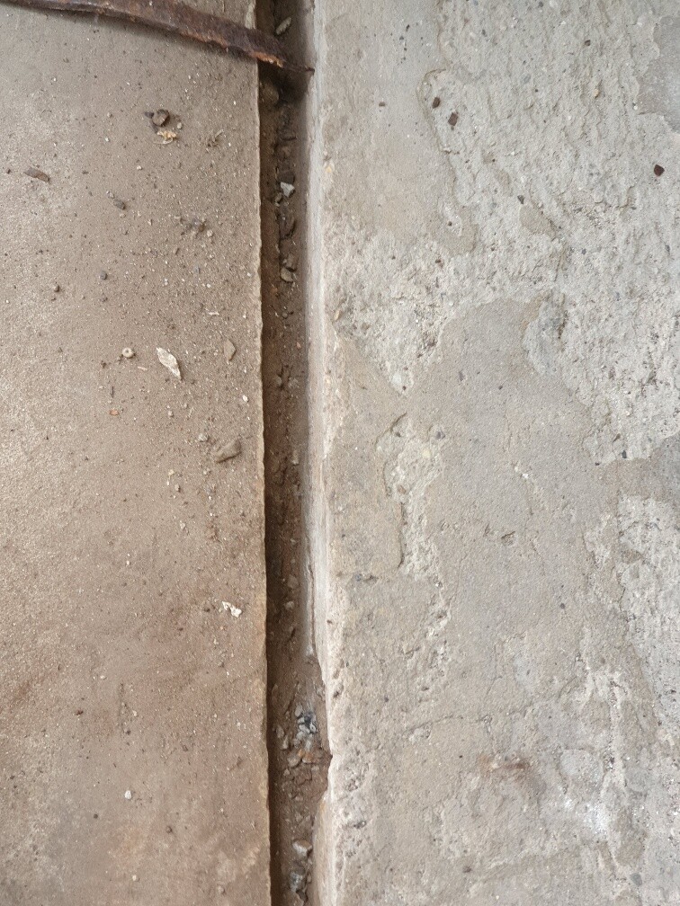 Narrow gap between two rough stone or concrete surfaces with dust particles.