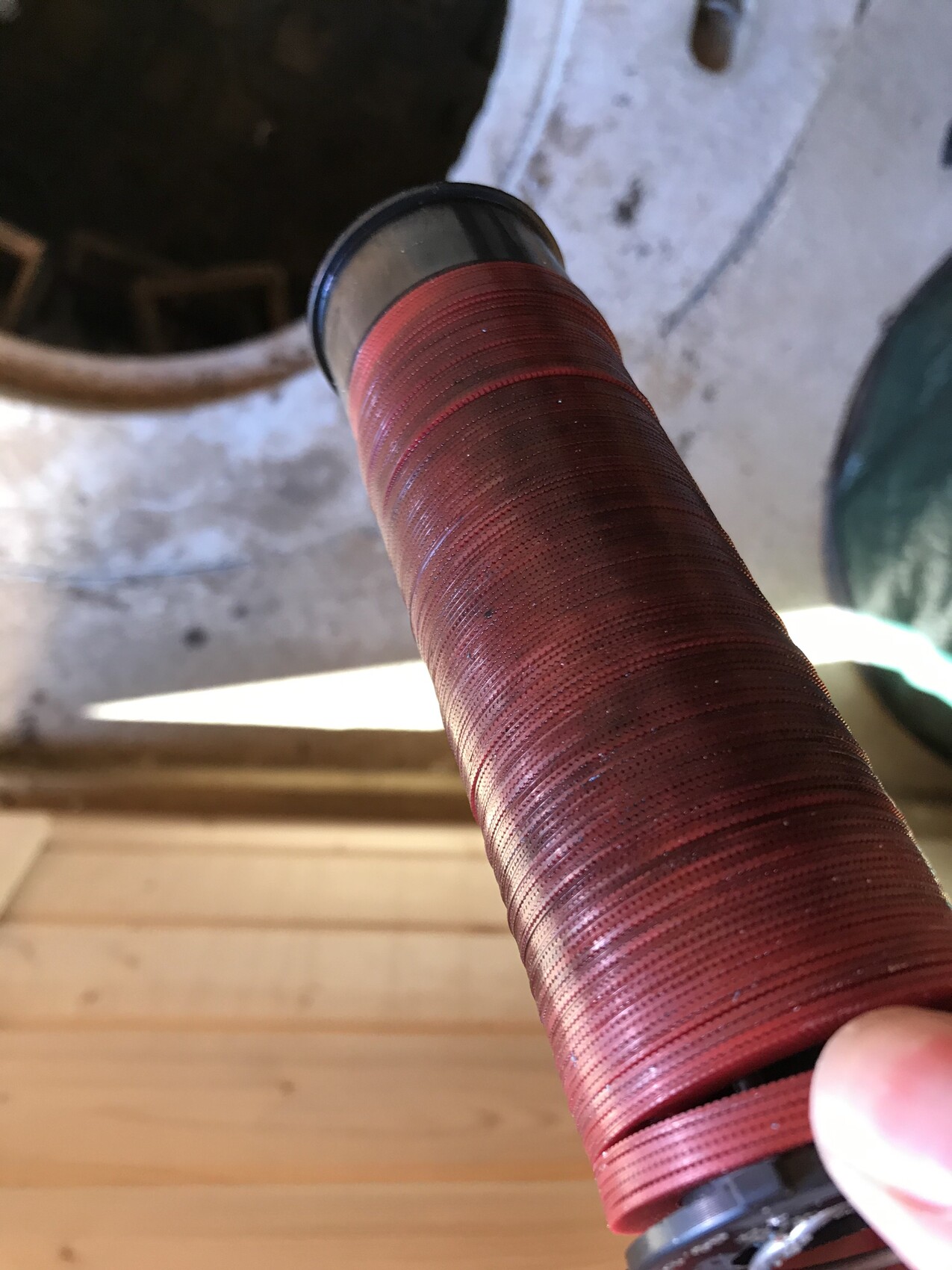 Close-up of a reddish-brown yarn/wire coil with black top edge, held by hand.