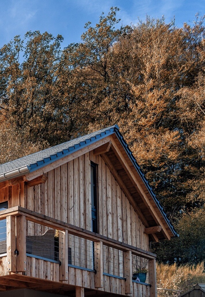 Wood house with balcony in front of autumn forest and blue sky